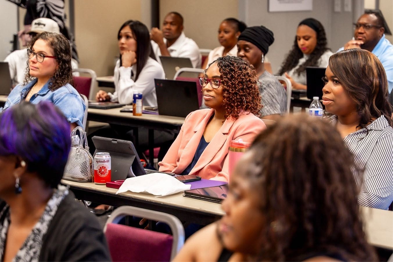Business owners seated at classroom tables listening closely during a B.I.D. Academy session.